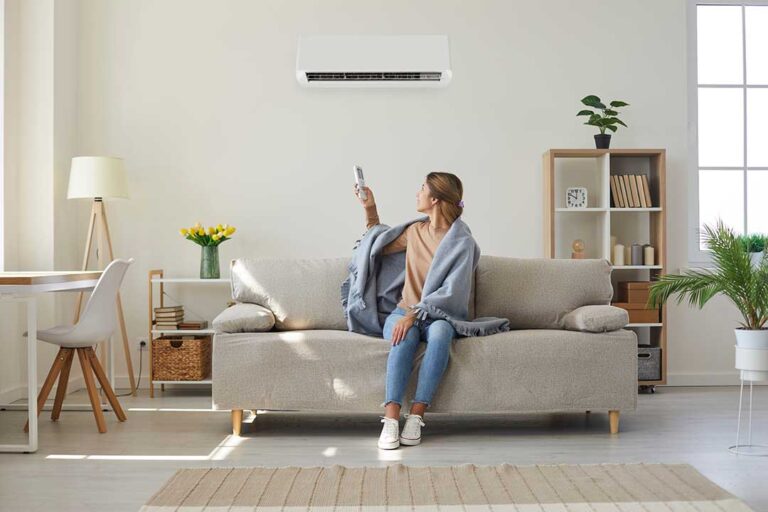 A person inspecting and changing a furnace filter in a home basement utility room.