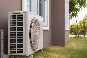 A technician inspects the outdoor unit of a residential heat pump in a suburban backyard during autumn.